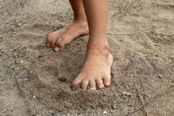 istock bare feet of a child on the sand 2174331974