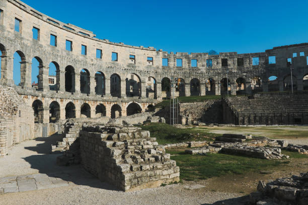 Visitors marvel at the well preserved Roman amphitheater in Pula Croatia where history meets stunning architecture on a sunny day.