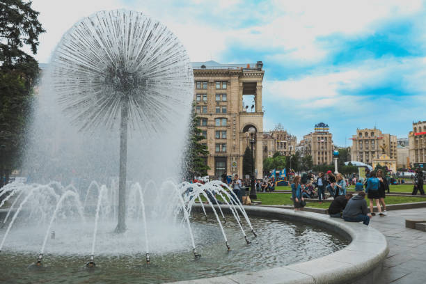Kyiv, Ukraine - May 25, 2018: Visitors gather around a stunning fountain art piece in the heart of Kyiv appreciating its beauty while enjoying a sunny day with a lively atmosphere.
