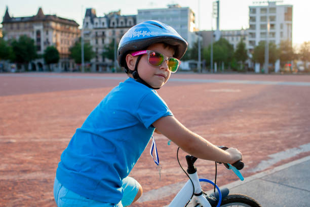 A happy youngster rides a bicycle in a vibrant city setting. The scene highlights the energy and well-being gained from cycling, promoting an active lifestyle with an emphasis on safety.