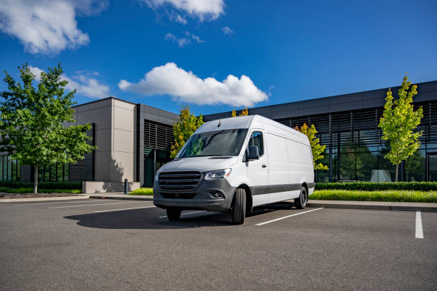 White cargo mini van making delivery to customer work place standing on the industrial parking lot stock photo
