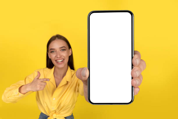 istock Cheerful Lady Showing Cellphone With Blank Screen Over Yellow Background 2174345624