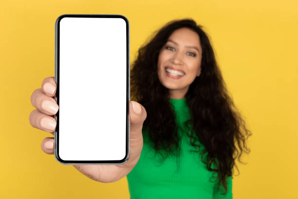 istock Cheerful Arabic Lady Showing Cellphone Blank Screen Over Yellow Background 2174345843