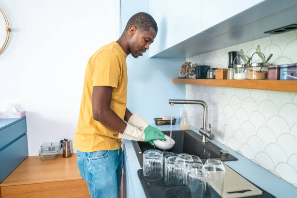 istock Conscientious Black Man Washing Dishes in Modern Kitchen 2174349308