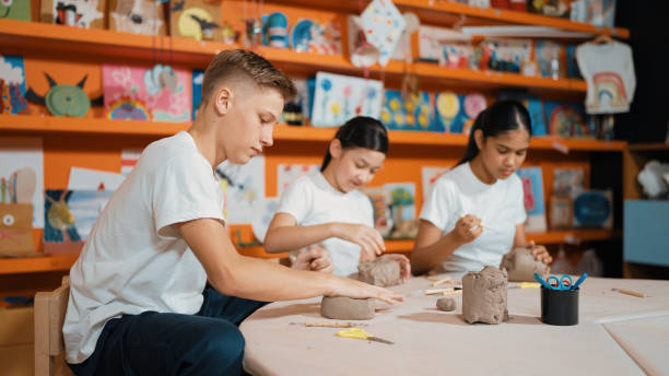 Group of happy smart diverse student working with clay at workshop. Edification.
