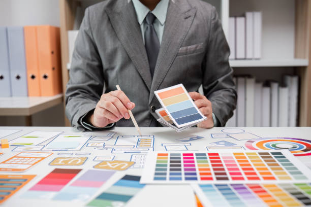 istock System Developer Analyzing UX UI Plans with Color Swatches and Design Layouts in a Modern Office Setting 2174361423