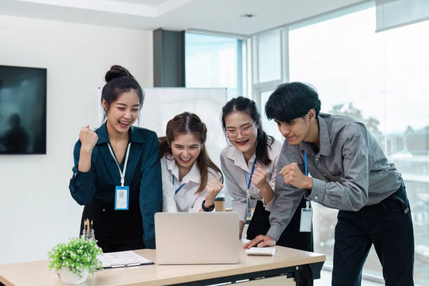 istock Young Professionals Celebrating Success in Modern Office Environment with Laptop and Documents 2174365415
