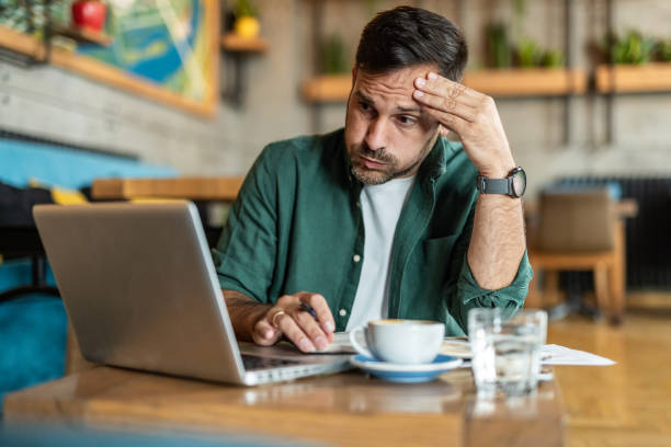 istock Balancing work and care: a man working in a cafe with a worried expression on his face 2174366464