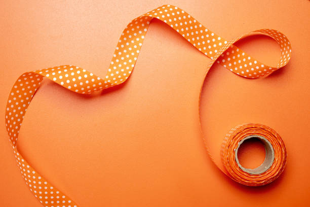 istock A long orange ribbon with white polka dots is lying 2174368080