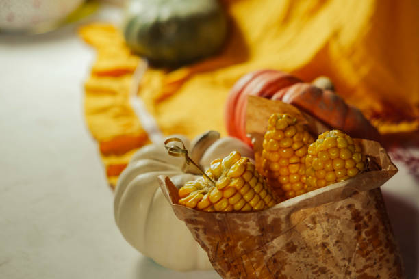sweet corn on cob cut in half boiled cooked served on plate in warm autumn fall colors with  small pumpkins