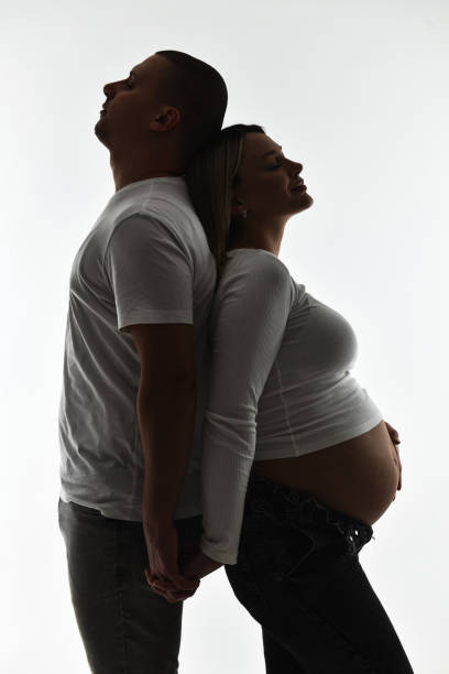 close up of pregnant couple making hand heart gesture on belly