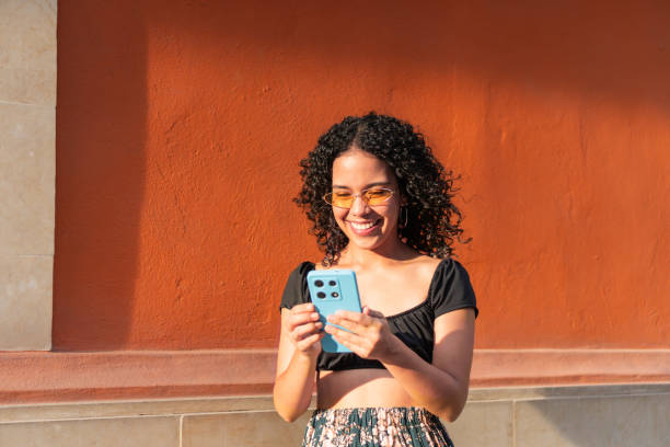 Smiling young woman using her smartphone outdoors