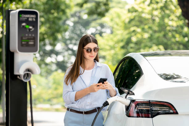 istock Young woman using smartphone to pay for electric car charging. Exalt 2174373200