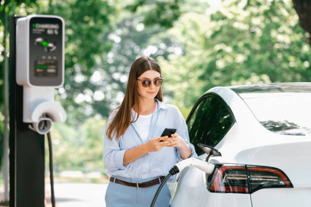 istock Young woman using smartphone to pay for electric car charging. Exalt 2174373412
