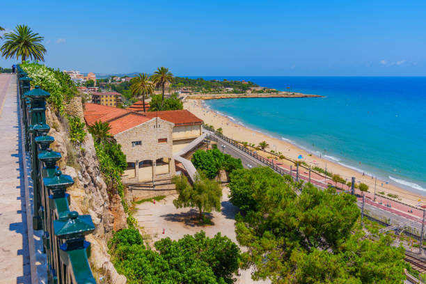 Charming view of beach with buildings and coastal path in Tarragona, Catalonia.