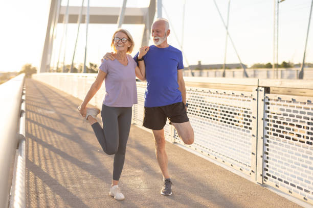istock Senior couple stretching quads with broad smiles on a sunny bridge 2174376976