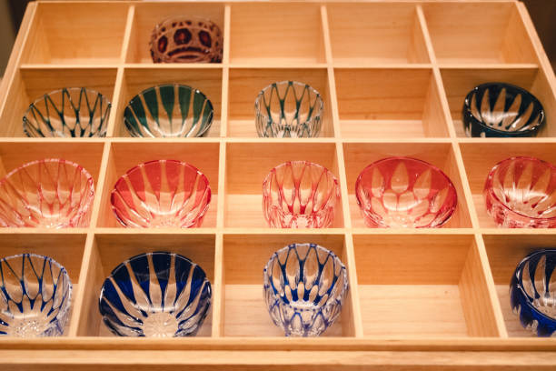 Several exquisitely crafted Japanese cut glass cups, neatly arranged in a partitioned wooden box. The vibrant colors and intricate designs reflect the rich cultural heritage and meticulous craftsmanship.