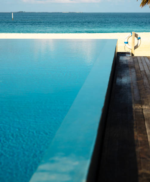 Infinity pool with lifebuoy and wooden stairs by the beach