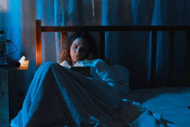 istock Insomnia, night reading. Sleepless woman reading book lying in bed at night. 2174380474