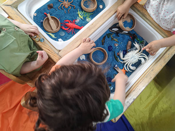Children playing with toys in sensory exploration table.