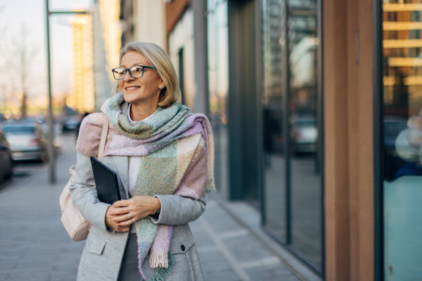 istock A cheerful senior business woman holds a digital tablet in her hands while walking in front of the office building where she works 2174383613