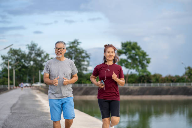 istock Two senior citizens are enjoying jogging on a walkway by a pond in a park. 2174384456