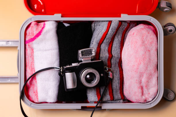 istock top view of open luggage with camera and clothes isolated on a coral background 2174386830