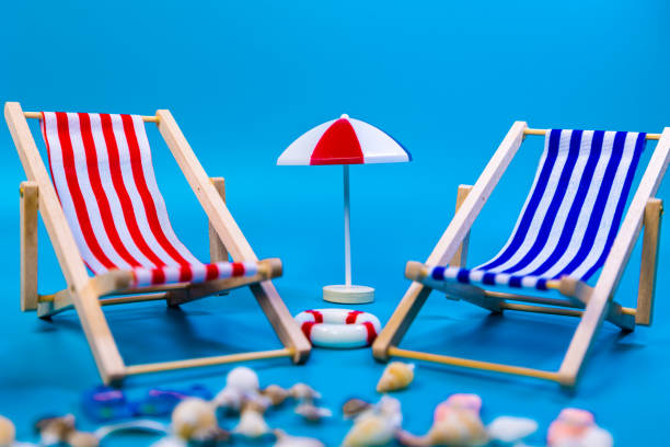 Close up of two red and blue hammocks with a red umbrella in the middle on a blue background, beach vacation concept