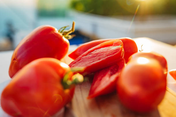A close-up shot of tomatoes of various shapes grown in a hydroponic greenhouse system. A cross-section of a tomato is also visible in the picture, with copy space