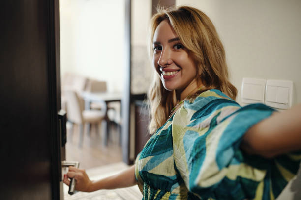 istock Smiling Woman Holding Door Handle and Looking Happy 2174394117