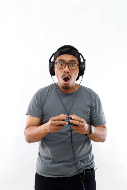 istock Asian gamer man with beard playing video game using joystick and headphones scared in shock with a surprise face, afraid and excited with fear expression 2174394428