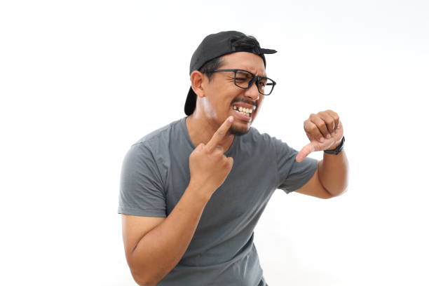 istock Unhappy Asian man pointing his missing teeth while showing thumbs down. Isolated on white 2174395406