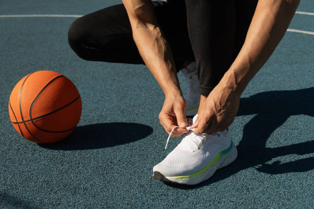 Basketball player tying running shoes shoelace before training.