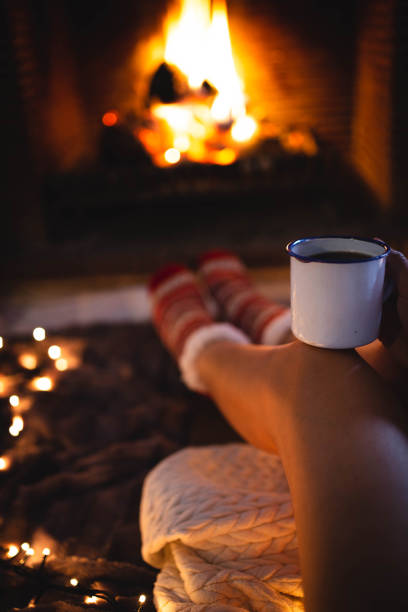 istock Faceless woman sitting by fireplace and holding mug 2174401376