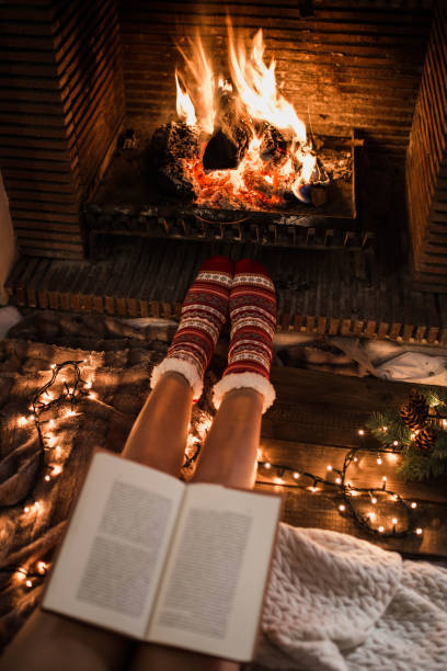 istock Unrecognizable woman sitting by fireplace and reading book 2174401404