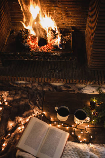 istock Unrecognizable woman sitting by fireplace and reading book 2174401427