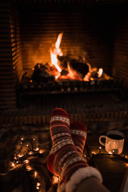 istock Faceless woman sitting by fireplace and holding mug 2174401428