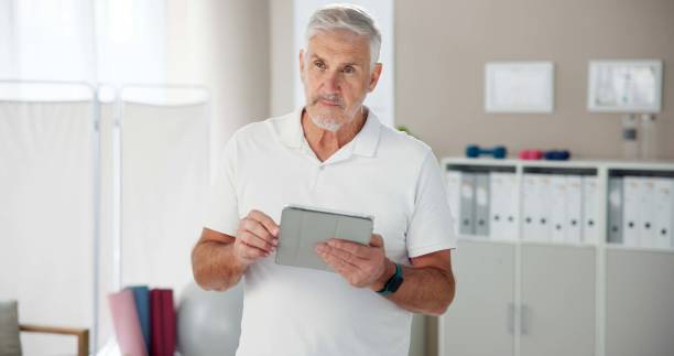 istock Physiotherapy, man and thinking with tablet in office for client, appointment or schedule information. Telehealth, worker and physiotherapist with tech for medical database, update or patient records 2174401915