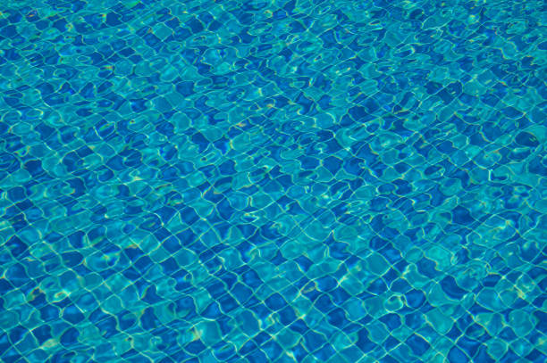 Swimming pool rippled water with sun reflections. Abstract background