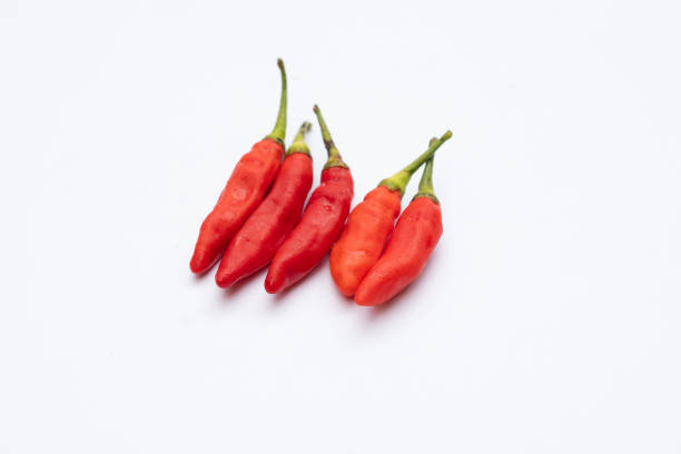 Red chili peppers lined up on a white background, showcasing their vibrant color and texture, perfect for food, spice, and culinary projects