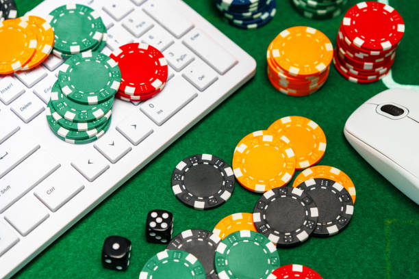 istock Chips and playing cards on a green felt surface near a computer keyboard during an online gaming session at home 2174404792