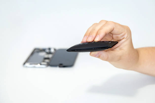 istock Hand holding a swollen phone battery with a disassembled phone blurred in the background 2174407325