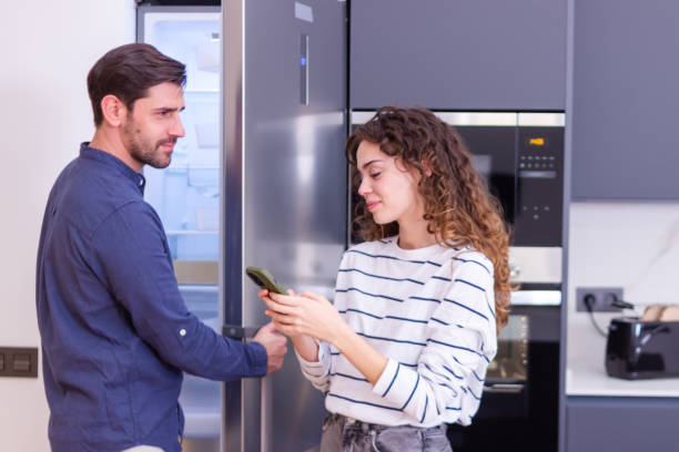 istock Couple checking grocery list on smartphone while looking inside fridge in kitchen 2174407426