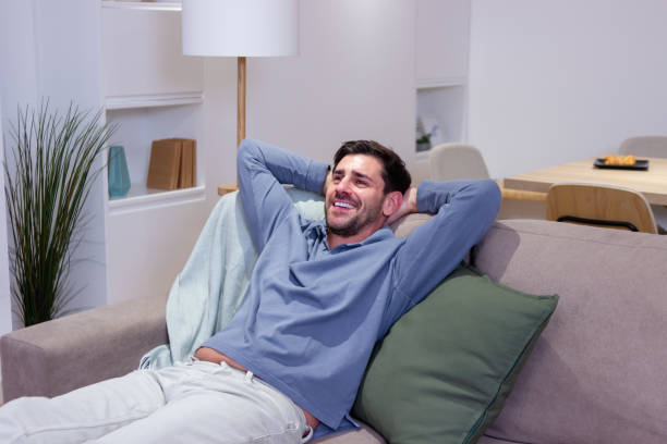 istock Handsome man relaxing on sofa at home smiling and looking away 2174410080