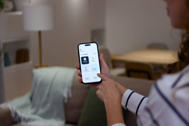 istock Woman controlling smart home devices using smart home application on mobile phone 2174411135