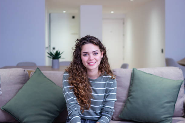 istock Young woman smiling while relaxing on couch at home 2174412253