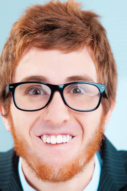 Studio close-up portrait of a 20 year old man in a blue plaid shirt with glasses on a yellow background