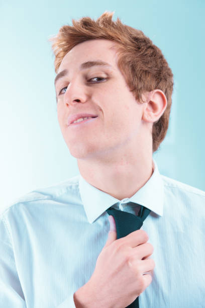 Young businessman loosening his tie with a playful smile on his face, enjoying a moment of relaxation and freedom in a corporate setting