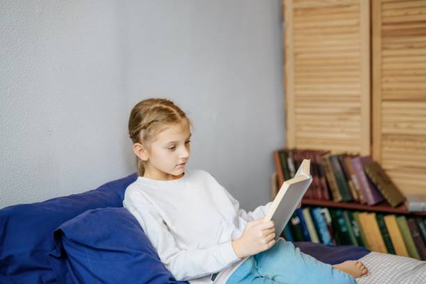 istock 10 year old girl reading a book on the bed 2174413992