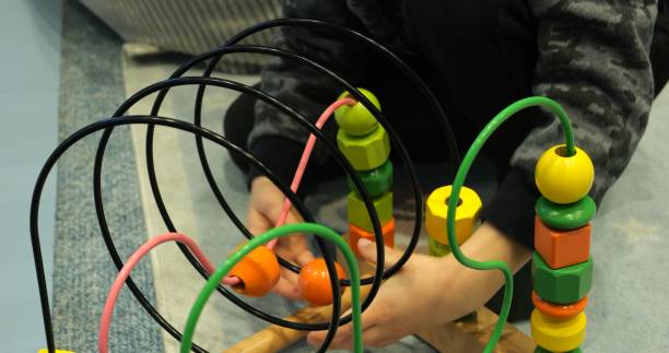 istock Little boy plays with colorful wire bead maze on floor 2174416665